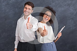 Two smiling happy businesspeople in formalwear showing thumbs-up