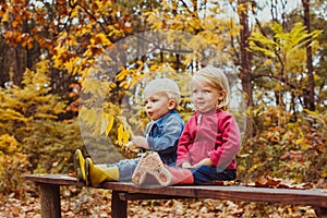 Two smiling happy kids friends, boy and girl sitting on the bench