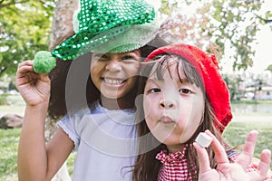 Two smiling happy little girl wear party hat eat candy