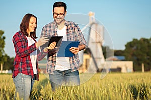 Two smiling happy young male and female agronomists or farmers talking in a wheat field photo