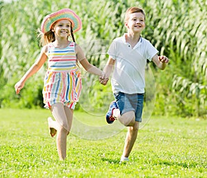 two smiling kids active playing and running outdoors