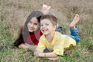 Two smiling kids on the autumn grass