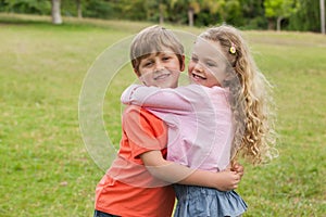 Two smiling kids hugging at park