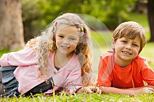 Two smiling kids lying at park