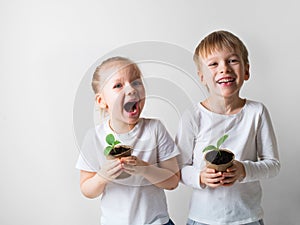 Two smiling kids with sprouts and gardening tools, ecology and environment theme on white background