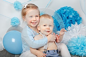 two smiling laughing hugging cute adorable Caucasian children, toddler girl and baby boy, celebrating birthday