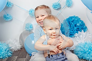 Two smiling laughing hugging cute adorable Caucasian children, toddler girl and baby boy, celebrating birthday