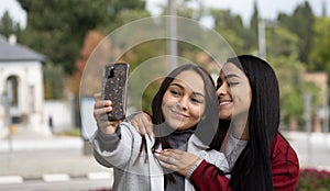 Two smiling lesbian couple latin women are taking a selfie together outdoors