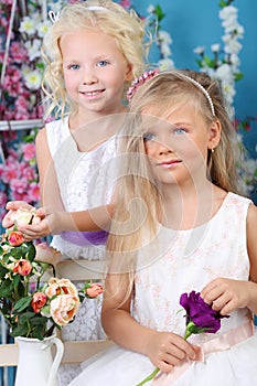 Two smiling little girls in white dresses hold
