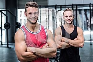 Two smiling muscular men with arms crossed
