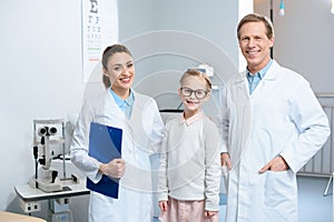 two smiling ophthalmologists and little child