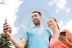 Two smiling people with smartphones outdoors