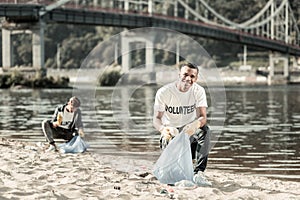 Two smiling responsible students cleaning up trash left behind on the beach