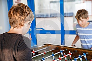 Two smiling school boys playing table soccer. Happy excited children having fun with family game with siblings or