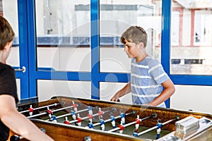 Two smiling school boys playing table soccer. Happy excited children having fun with family game with siblings or