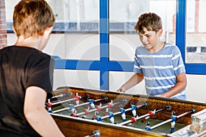 Two smiling school boys playing table soccer. Happy excited children having fun with family game with siblings or