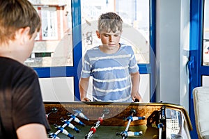 Two smiling school boys playing table soccer. Happy excited children having fun with family game with siblings or