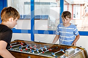 Two smiling school boys playing table soccer. Happy excited children having fun with family game with siblings or