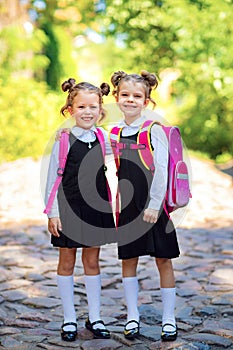 Two Smiling student girl wearing school backpack. Portrait of happy Caucasian young girl outside the primary school