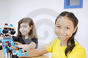 Two smiling students with  a Lego robot in class
