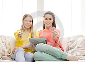 Two smiling teenage girls with tablet pc at home