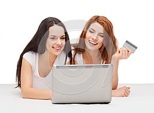 Two smiling teenagers with laptop and credit card