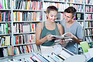 Two smiling teenagers reading book together