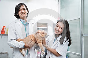 two smiling vets looking at camera while checking cat