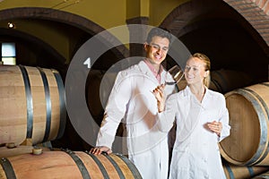 Two smiling wine house workers checking quality of product