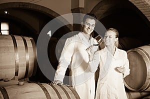 Two smiling wine house workers checking quality of product