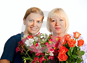 Two smiling women with flowers on white background