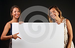 Two smiling women holding a blank banner