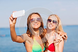 Two smiling women making selfie on beach