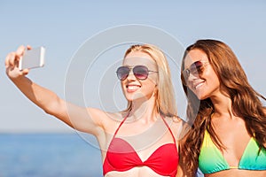 Two smiling women making selfie on beach