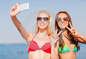 Two smiling women making selfie on beach