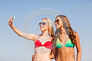 Two smiling women making selfie on beach