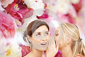 Two smiling women whispering gossip