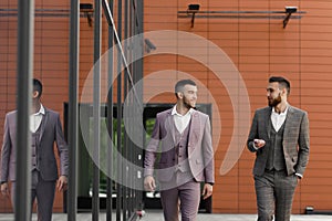 Two smiling young businessmen walking and talking in the city