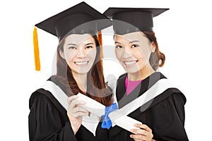 Two smiling young graduate students holding a diploma