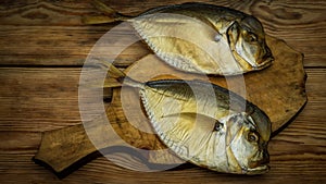 Two smoked fish on a wooden cutting board