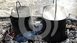 Two smoldering cauldrons with hot watet on charcoal in slow motion.