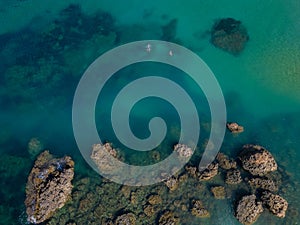 Two snorkelers in turquoise sea near the rocks in Malta aerial top down