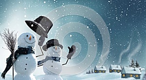 Two snowmen standing in winter Christmas landscape.