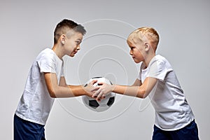 two soccer players boys holding the same ball in hands