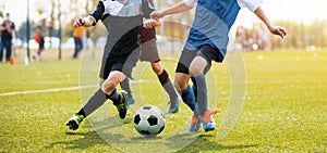 Two soccer players running and kicking a soccer ball. Legs of two young football players on a match