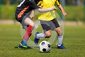 Two soccer players running and kicking a soccer ball. Legs of two young multiracial football players on a match