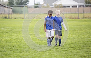 Two soccer teammates walking off the field after a loss photo