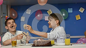 Two soiled boys funny eat cake at the festive table