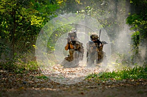 Two soldiers with the fighting uniform sit on the ground and point gun to target for the concept war battle in jungle photo