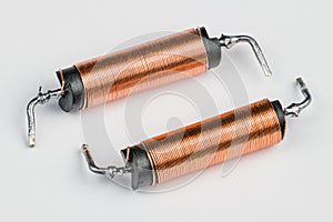 Two solenoids with helical copper wire wound on black coil on white background